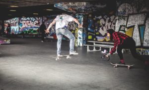Man in White Shirt on Black Skateboard Doing Tricks