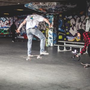 Man in White Shirt on Black Skateboard Doing Tricks