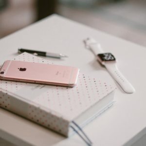 Rose Gold Iphone 6 S on Top of White Covered Book