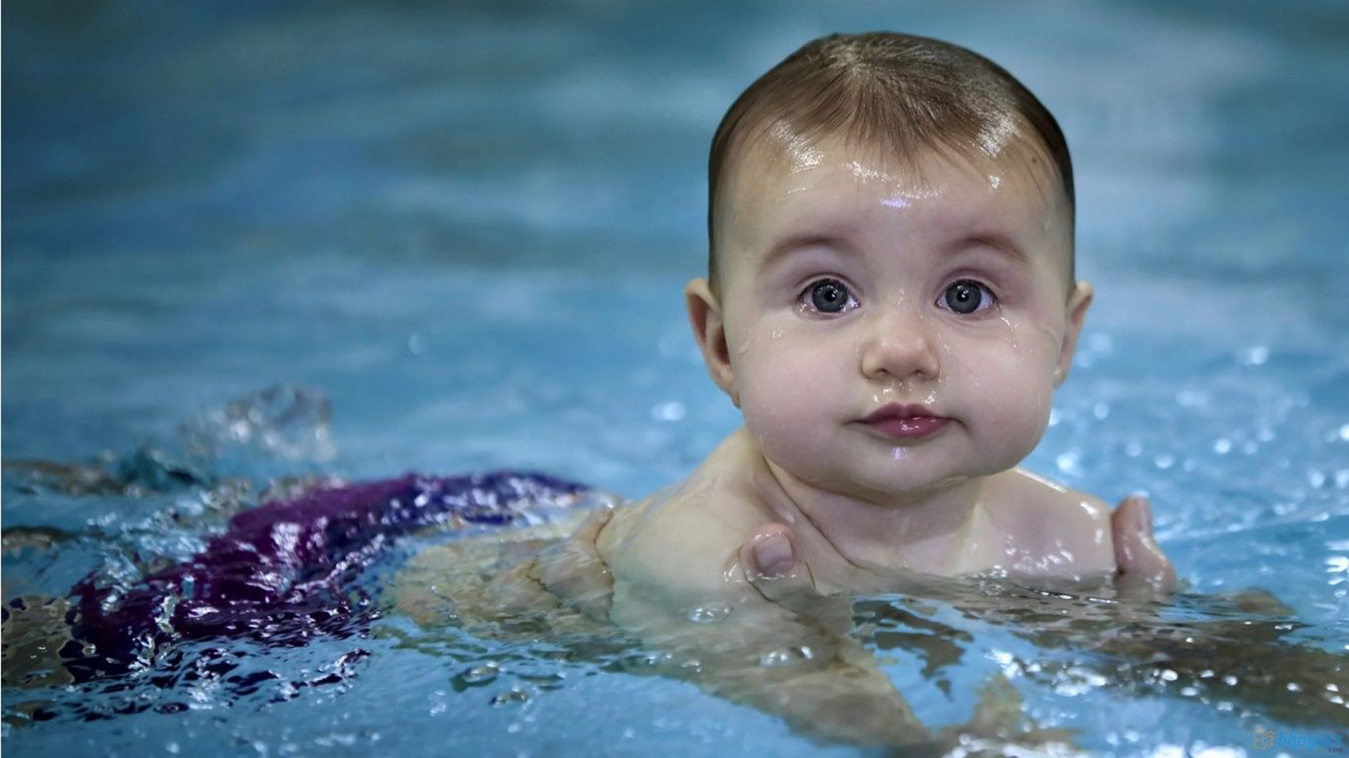 Cute Baby Is Swimming On Body Of Water Wearing Purple Shorts In A Blur
