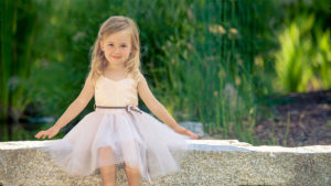 Cute Little Girl Is Wearing White Dress Sitting On Stone Pavement In Green Blur Background HD Cute