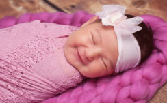 Smiley Cute Closed Eye Baby Is Covered With Pink Netted Towel And Having White Ribbon Band On Head HD Cute Wallpapers