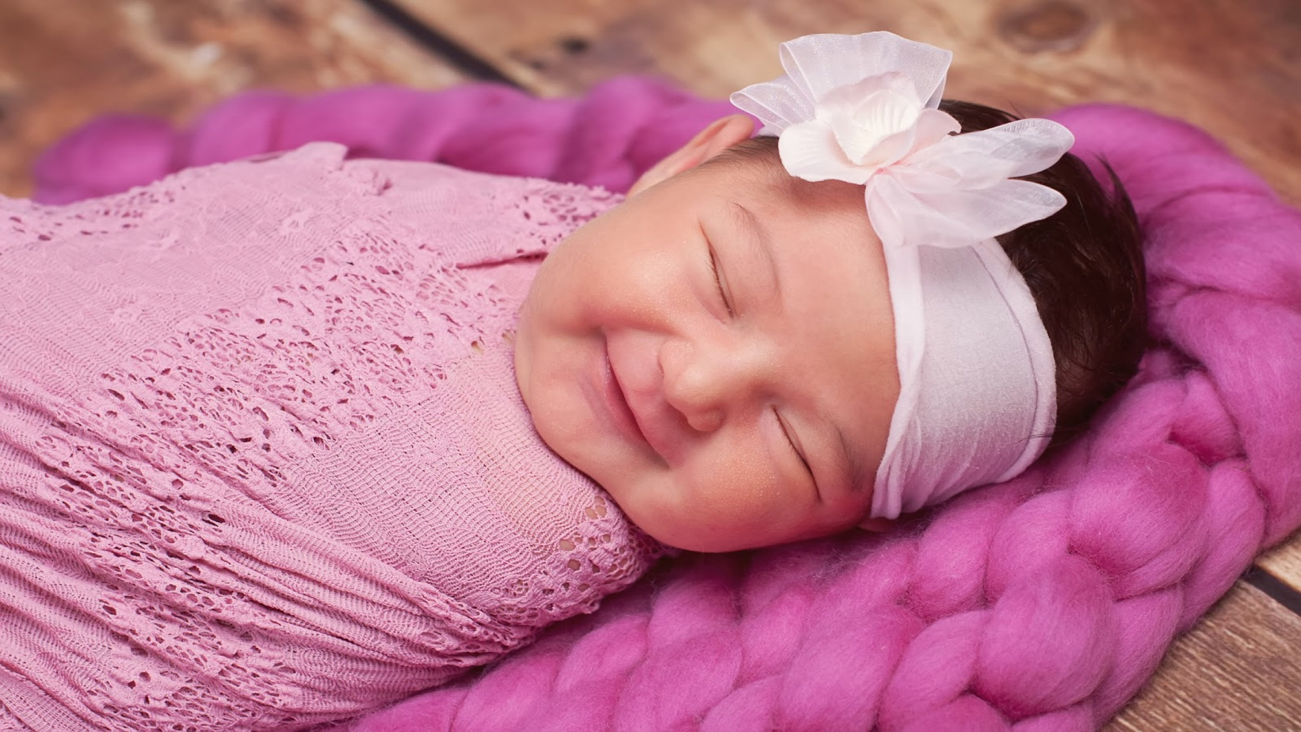Smiley Cute Closed Eye Baby Is Covered With Pink Netted Towel And Having White Ribbon Band On Head HD Cute