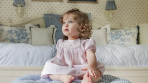 Cute Ash Eyes Baby Girl Is Sitting On Bed Wearing Pink Dress HD Cute
