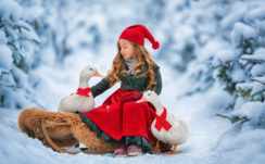 Cute Little Girl Is Wearing Santa Claus Dress And Cap Sitting With Goose In Snow Background HD Cute