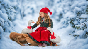 Cute Little Girl Is Wearing Santa Claus Dress And Cap Sitting With Goose In Snow Background HD Cute