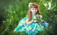 Cute Little Girl With Flowers Is Sitting On Green Grass Wearing Colorful Flowers Printed Dress HD Cute Wallpapers
