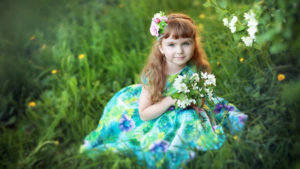 Cute Little Girl With Flowers Is Sitting On Green Grass Wearing Colorful Flowers Printed Dress HD Cute