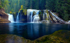 Beautiful Waterfalls On Green Algae Covered Rocks Pouring On River In Green Trees Forest Background