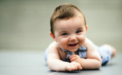 Cute Smiley Baby Is Lying Down On Floor Wearing Light Blue Dress In A Blur Background HD Cute